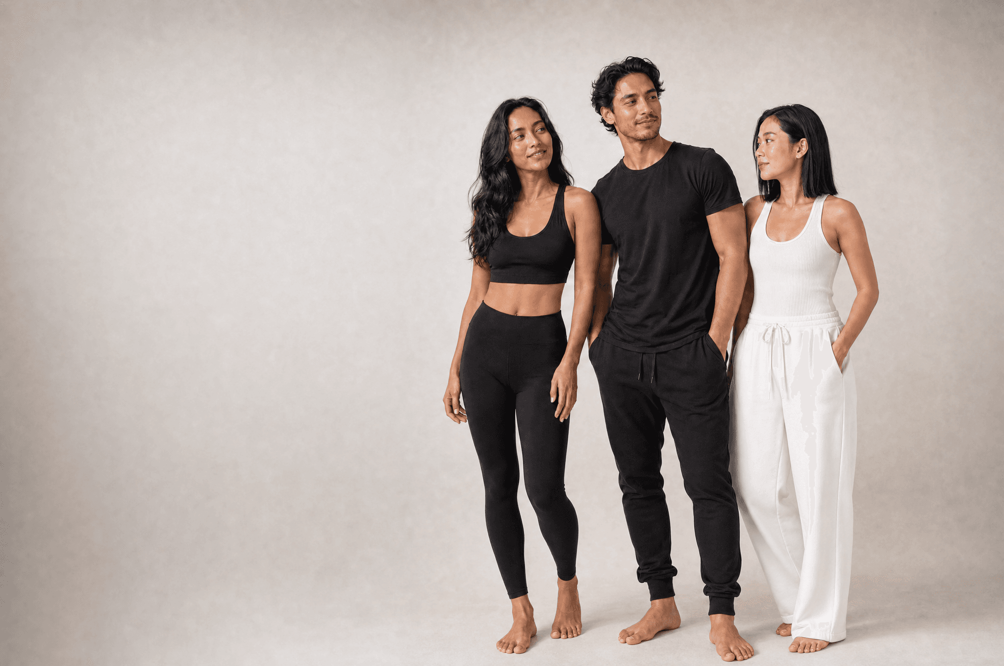 Three people standing loosely together in a white studio, one looking at camera